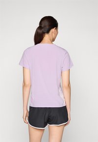 Lavender sport t-shirt met korte mouwen, met kleine perforaties, gecombineerd met zwarte shorts met witte details.