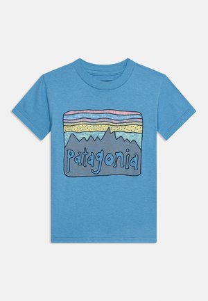Camiseta azul de manga corta con un diseño de montaña multicolor y la palabra "Patagonia" en texto estilizado en el frente.