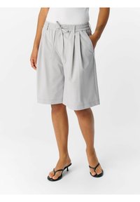 Pantaloni shorts grigi chiari realizzati in tessuto morbido, con vita regolabile tramite cordoncino e pieghe, dotati di tasche laterali e design lunghezza ginocchio.