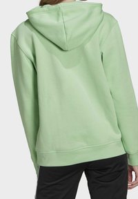 Mintgrön huvtröja med stor huva, strukturerad tyg och ribbade muddar. Har en avslappnad passform och en känguruficka framtill.