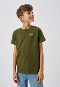 T-shirt en coton vert à manches courtes. Présente un col rond et un petit logo blanc "T.W.S.N." sur la poitrine. Texture lisse, coupe décontractée.