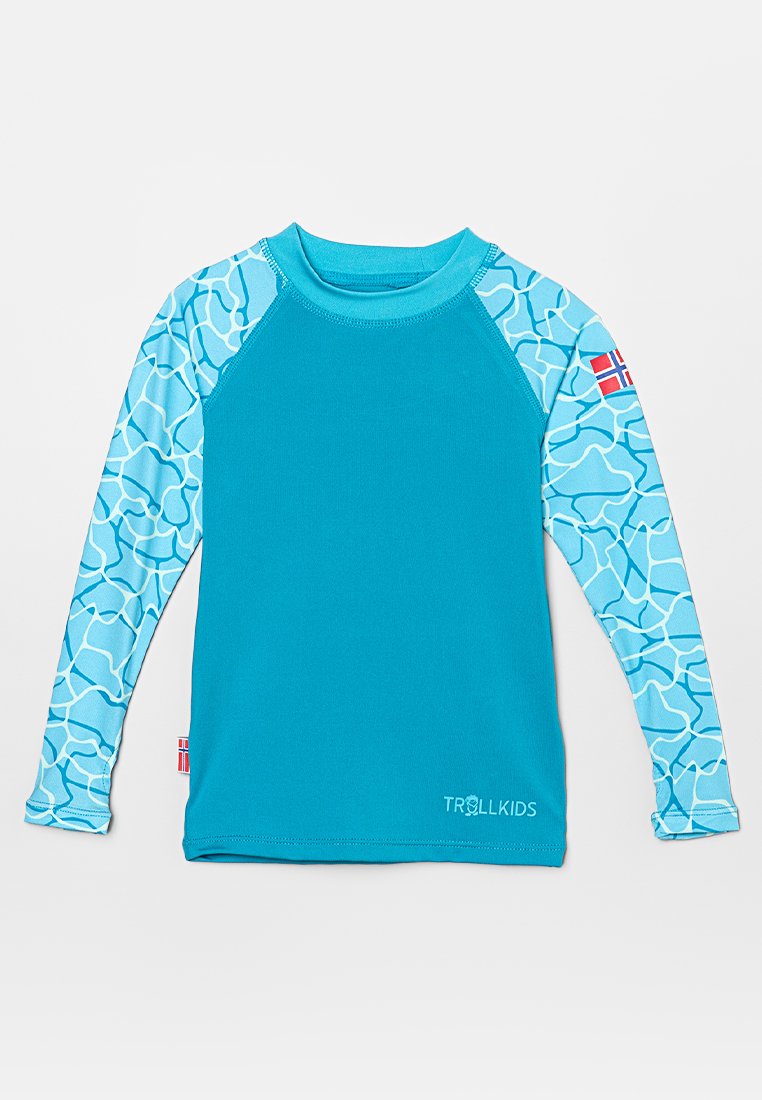 Blå långärmad rash guard för barn med ljusblå mönstrade ärmar, Trollkids-logga nära fållen och norsk flagga på vänster ärm.