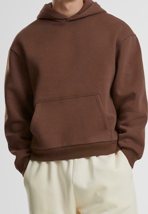 Sweatshirt à capuche marron en tissu doux, doté d'une poche kangourou, de poignets et d'un ourlet côtelés, avec une coupe décontractée et un design minimaliste.