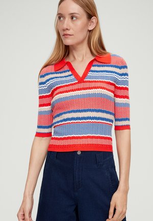 Pullover en maille avec des rayures en zigzag rouges, bleues et crème, manches courtes et col en V, complété par un ourlet côtelé.
