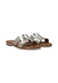 Metallic sølvfarvede hælende sandaler med to brede stropper og udskæringer, placeret på en brun flad sål. Glat tekstur med et minimalistisk design.