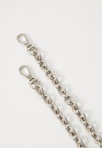 Metallist kett, millel on kaks klambrit, ovaalsed lingid ning särav hõbedane viimistlus. Sile tekstuur ja poleeritud pinnad.