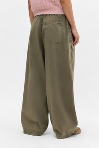 Pantalones holgados de color verde oliva, hechos de una tela suave, que cuentan con un bolsillo trasero y una cinturilla elástica para mayor comodidad. Los acentos incluyen puños fruncidos.