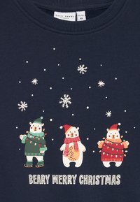 Granatowa bluza z trzydziestoma kreskówkowymi niedźwiedziami w świątecznych strojach, otoczoną płatkami śniegu, z napisem "BEARY MERRY CHRISTMAS" poniżej.