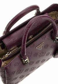 Sac à main en simili cuir violet avec motif logo en relief, poignées supérieures doubles, poche zippée intérieure et accents en métal doré.