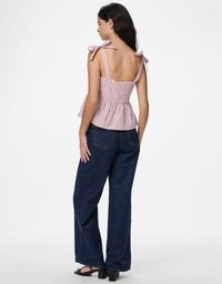 Top peplo a righe con spalline a fiocco, dotato di un corpino aderente e orlo svasato. Abbinato a jeans in denim scuro a gamba larga e sandali con tacco a blocco.