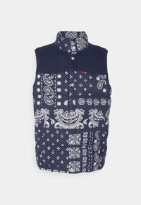 Mörkblå ärmlös pufferväst med vita paisley- och blommönster i lapptäcksteknik samt metallknappar längst fram.