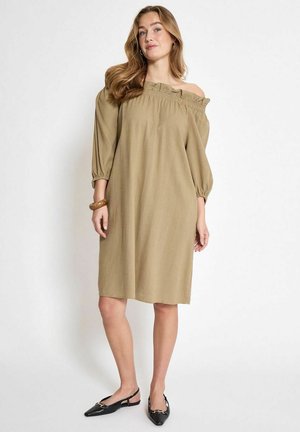 Abito kaki con scollo a spalla, maniche a sbuffo, scollatura arricciata e vestibilità comoda, abbinato a scarpe slingback nere e un braccialetto marrone.