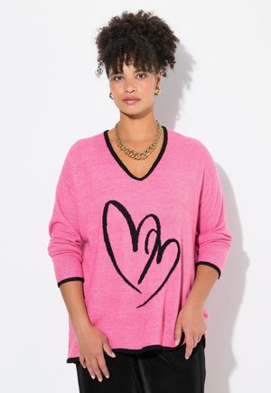 Roze gebreide trui met een V-hals en zwarte accenten. Heeft een groot zwart hartontwerp op de voorkant en ribbelmanchetten.