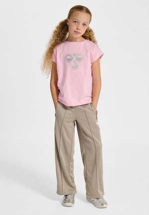 Różowy t-shirt z krótkim rękawem i srebrnym nadrukiem na środku, w połączeniu z beżowymi spodniami o luźnym kroju z kieszeniami zapinanymi na zamek.