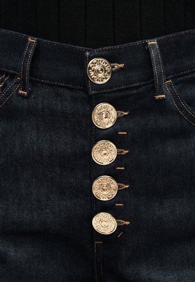 Σκούρο τζιν παντελόνι με πέντε εμφανείς μεταλλικές κουμπιές χαραγμένες με "DON DUP" και μπεζ ραφές κατά μήκος των ραφών και των κουμπότρυπων.