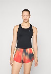 Top deportivo negro de tirantes con escote redondeado, combinado con pantalones cortos coloridos que presentan un patrón degradado de rojo, naranja y amarillo.