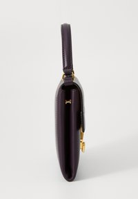 Purple leather handbag with a smooth texture, gold hardware accents, and a slim design. Features a short handle for carrying.
