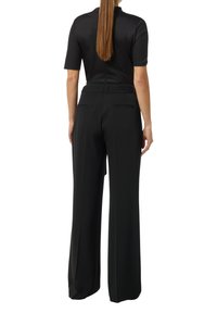 Black, high-waisted trousers with a straight fit. Features side pockets and a smooth texture. Pairing with a fitted black top.