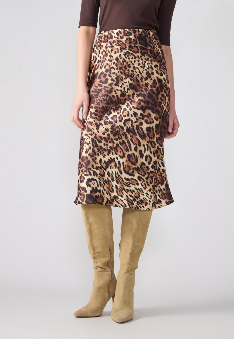 Satin midi suknja s leopard uzorkom i lepršavim rubom, u kombinaciji s bež suknjicama do koljena s potpeticama. Glatka tekstura i odvažan uzorak.