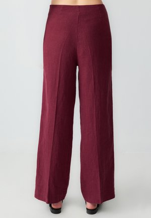 Pantalons larges en tissu bourgogne foncé avec une finition texturée et un détail de couture centrale, dotés d'une taille haute et d'une coupe ample.