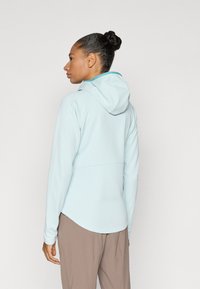 Ανοιχτό γαλάζιο φούτερ με αντίθετη επένδυση, με εφαρμοστό σχεδιασμό, μακριά μανίκια και κυρτή γωνία. Λεία υφή και καθημερινό στυλ.