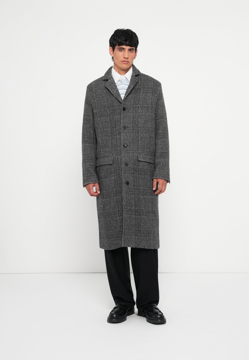 Gray plaid coat with a tailored design, featuring long sleeves, a collar, six buttons, and two front pockets. Smooth texture.