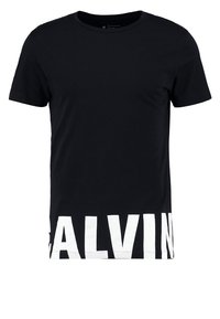 Svart T-shirt med kort ärm och stor vit delvis text "CALVIN" på framsidan i botten.