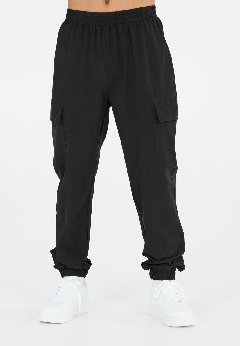 Svarta cargobyxor med elastisk midja, två sidofickor, avsmalnande anklar och ett mjukt, lätt material. Bärs med vita sneakers.