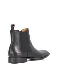 Zwarte leren Chelsea boot met elastische zijpanelen, trekriem aan de achterkant, lage hak en een gladde, ronde neus, tegen een witte achtergrond.