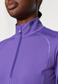 Veste zippée violette en tissu lisse et extensible. Présente un col montant, des accessoires en argent et le logo "BOGNER" sur l'épaule.
