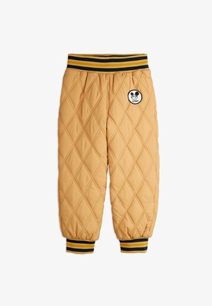 Calças amarelas acolchoadas com um padrão de diamante, apresentando um emblema circular preto e branco e uma cintura elástica listrada.