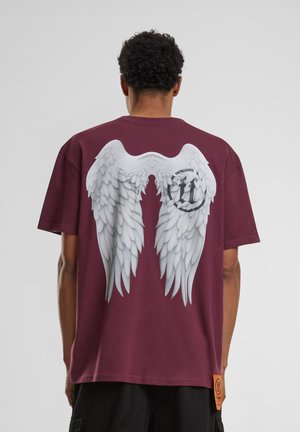 Bordeaux rode T-shirt met een groot, wit engelenvleugelontwerp op de achterkant, met een logo nabij de onderkant en een relaxte pasvorm.