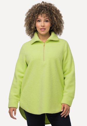 Vihreä limen värinen fleece-poolo, jossa on vetoketjukaulus, pitkät hihat ja pyöristetty helma. Teksturoitu kangas pehmeällä pinnalla.