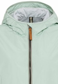 Licht mintgroene hoodie met een grijze binnenkant, voorrits en een bruin leren accent op de rits. Smooth textuur, lichtgewicht stof.
