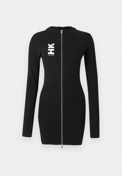 Vestido justo preto de manga longa com fecho prateado na frente e logo "HK" em branco com texto pequeno no lado esquerdo do peito.