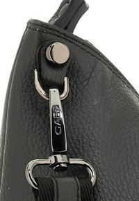 Dettaglio di una borsa a mano in pelle nera texturizzata con una chiusura in argento lucido e branding. Presenta cuciture lungo il bordo e hardware della tracolla resistente.