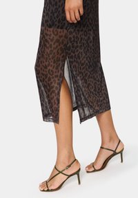 Black leopard print sheer maxi dress with side slit and green strappy heels, featuring thin straps and stiletto heels.