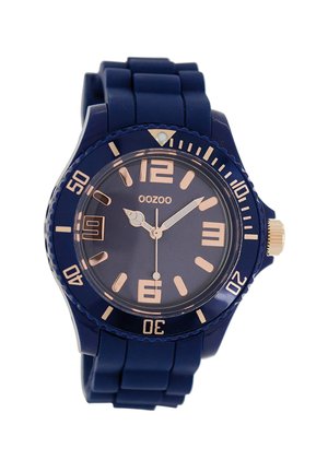 Montre en silicone marine avec un cadran rond, des aiguilles et des indices en or rose, et une lunette rotative avec des chiffres. Elle dispose d'un guichet de date à 3 heures.