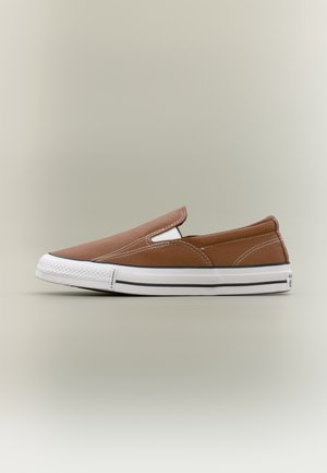Brun slip-on lærredsneaker med hvid gummisål og sort kant, set fra siden på en neutral baggrund.