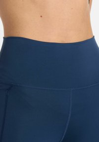 Leggings sportive blu navy a vita alta realizzati in tessuto morbido ed elastico, con cuciture piatte e un design minimalista.