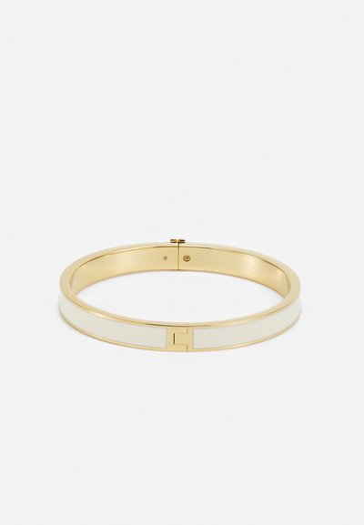 Kuldtooni bangles, millel on kahe tooniga disain valgete emailiga aktsentidega ja sile, poleeritud viimistlus. Klambri sulgemine on nähtav.