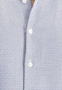 Camicia a bottoni bianca e azzurra a quadri, con piccoli bottoni e una trama di tessuto texturizzata.