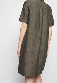 Lyhythihainen pellavamekko tumman maanläheisessä ruskeassa. Ominaisuuksiin kuuluu rento istuvuus, kaulus ja takasauman sauma. Teksturoitu kangas luonnollisella viimeistelyllä.