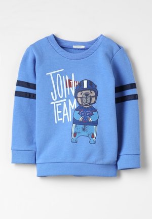 Sweat-shirt pour enfants bleu clair avec des rayures bleu foncé sur les manches, un ours en tenue de football, et le texte "REJOIGNEZ L'ÉQUIPE" sur le devant.