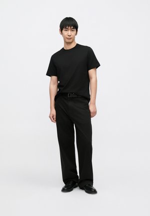 Black t-shirt paired with black, loose-fitting pants and black shoes. The outfit features a simple design and a smooth texture.