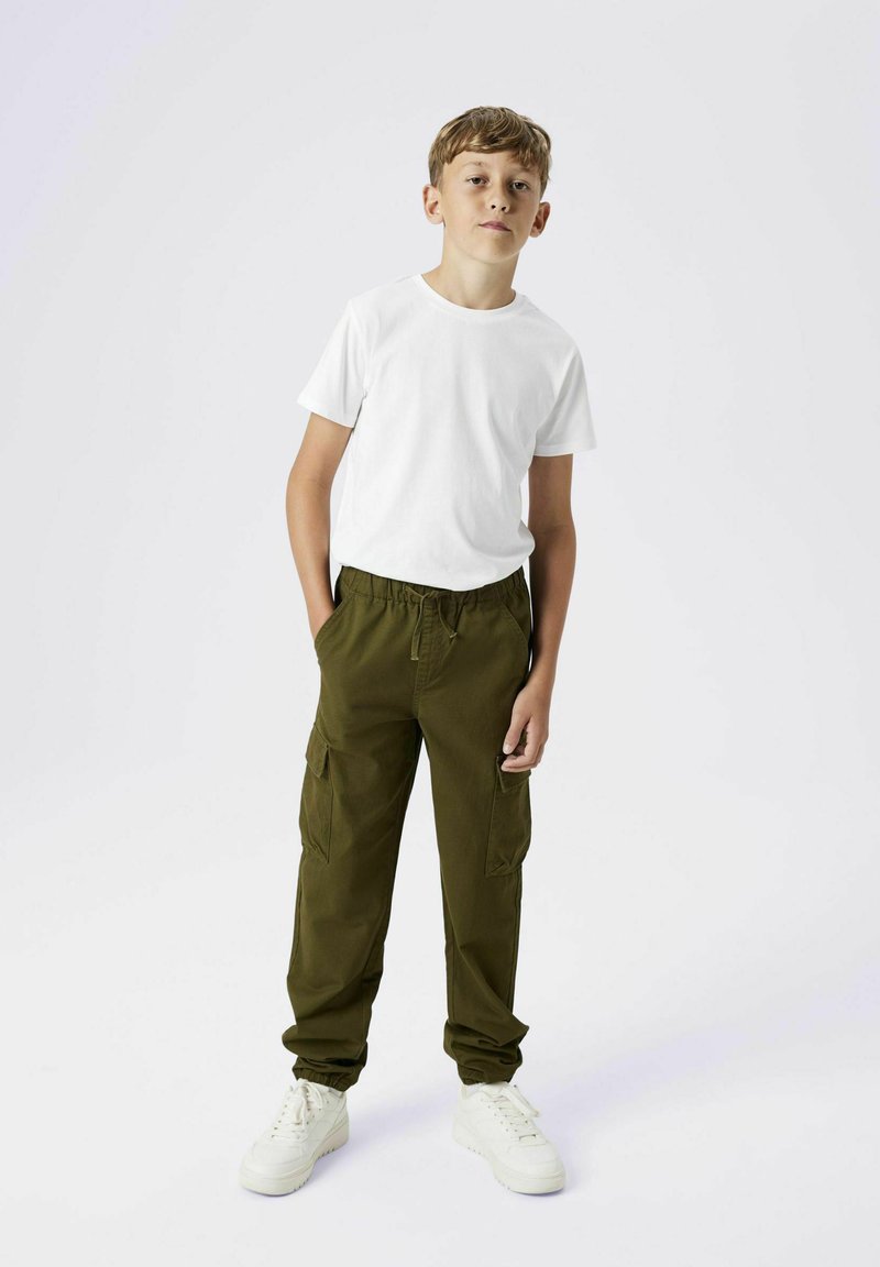 Hvid crew-neck t-shirt parret med olivegrønne cargo-bukser med sidelommer og elastiske manchetter, suppleret af hvide sneakers.