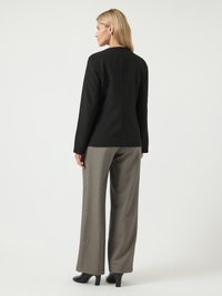 Black tailored blazer with long sleeves, smooth texture, round neckline, paired with light gray wide-leg trousers and black heeled boots.