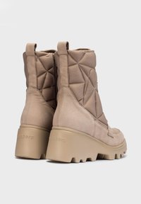 Botas de tobillo acolchadas beige con puntera redondeada y parte superior texturizada. Presentan una suela plataforma gruesa y una cremallera interior para el cierre.