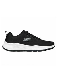 Zapatos deportivos negros con parte superior de tela texturizada, suela blanca y negra, y un sutil detalle del logo en el lateral. Diseño con cordones y lengüeta.