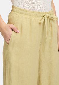 Lichtgele linnen broek met een elastische tailleband en verstelbaar trekkoord, voorzien van zijzakken en een relaxed fit.